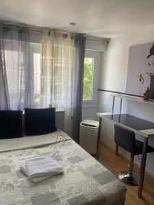 a bedroom with a bed and a desk and a window at Zola in Villeurbanne