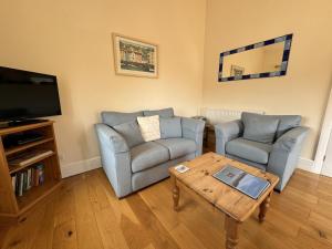 a living room with two chairs and a coffee table at Shippon End - Barn conversion with character and charm in Dittisham