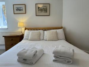 a bedroom with a white bed with towels on it at Shippon End - Barn conversion with character and charm in Dittisham