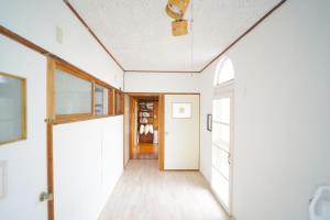 un pasillo con paredes blancas y una puerta blanca en AKARIYA Home&Hostel en Karatsu