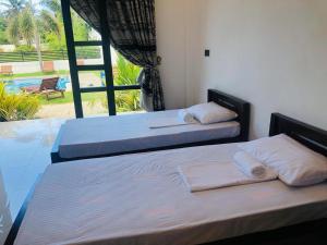 two beds in a bedroom with a view of a pool at Crocotopond in Arugam Bay