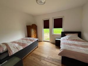 a bedroom with two beds and two windows at LiFarm in Aerzen