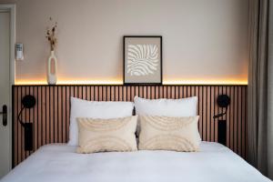 um quarto com uma cama com lençóis brancos e almofadas em Stadsherberg de Poshoorn em Maastricht