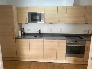a kitchen with wooden cabinets and a sink and a microwave at Indomitable in Colindale