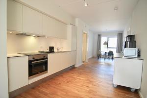 a kitchen with white cabinets and a wooden floor at Fantastic 2-bed w balcony in Ørestaden in Copenhagen
