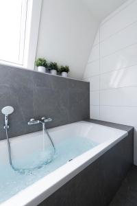 a bathroom with a bath tub with a window at Stadsherberg de Poshoorn in Maastricht