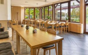 un restaurante con mesas y sillas de madera y ventanas en Benedikt Most en Most