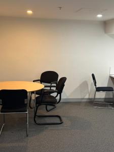 a room with chairs and a table and a wall at Studio Apartment in Melbourne CBD in Melbourne