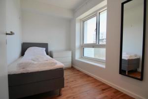 a small bedroom with a bed and a mirror at Great 2-bed w balconies and awazing views in Copenhagen