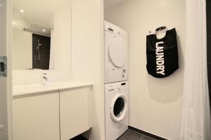 a white bathroom with a washing machine and a black bag at Great 2-bed w balconies and awazing views in Copenhagen