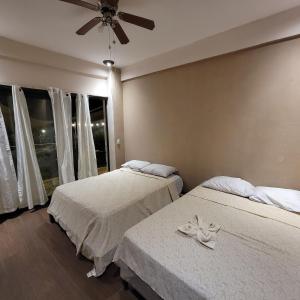 sypialnia z 2 łóżkami i wentylatorem sufitowym w obiekcie Restaurante y Hostal Romayor w mieście Santa Ana