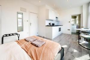 Habitación blanca grande con cama y cocina en City studios london en Londres