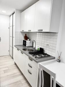 a white kitchen with white cabinets and a sink at Studio apartman Medvedgrad in Zagreb