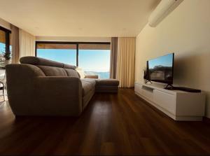 ein Wohnzimmer mit einem Sofa und einem Flachbild-TV in der Unterkunft Encosta do Gerês Village in Braga