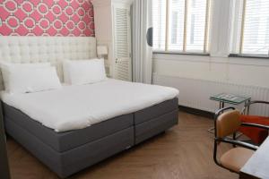 a bedroom with a large bed with a red headboard at Hotel New York by WestCord in Rotterdam