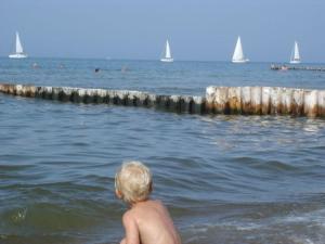 a young boy standing in the water at the beach at Bungalow mit Terrasse in Ostseenähe und eigenem Spielplatz in Wobbelkow