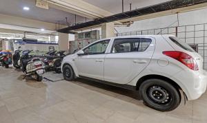 a white car parked in a garage with motorcycles at Treebo Trend Trinitywood in Bangalore