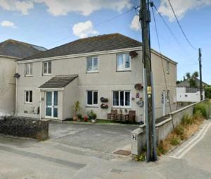 a white house with a pole in front of it at Top Location Perranporth Apartment in Perranporth