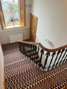 a staircase with a patterned carpet and a window at Morven Guest House Carnoustie in Carnoustie