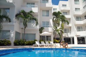 una persona sentada en una piscina frente a un edificio en Adhara Express, en Cancún
