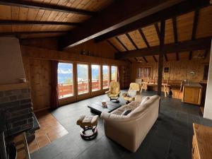 ein Wohnzimmer mit einem Sofa, Stühlen und einem Tisch in der Unterkunft Chalet rose des vents in Crans-Montana