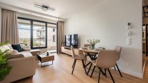 Flatbook - City Center Apartments Doki Living في غدانسك: غرفة معيشة مع أريكة وطاولة مع كراسي