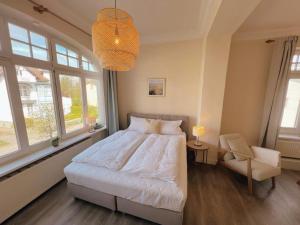 a bedroom with a bed and a chair and windows at Appartementhaus Plueckhahn in Kühlungsborn