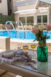 une table avec deux verres de vin et un vase de fleurs dans l'établissement Apartments Del Mar, à Petrovac na Moru