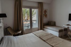 um quarto de hotel com uma cama e uma janela em Hotel Bougainvillier Djerba em Taguermess