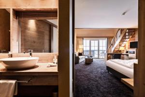un bagno con lavandino e un letto in una camera di Panoramahotel Oberjoch a Bad Hindelang