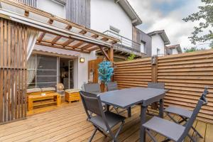 patio con tavolo e sedie su una terrazza in legno di Atlantic Selection - Un séjour à la Villa Sharon avec terrasse et parking a Capbreton