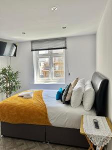um quarto com uma cama com almofadas e uma janela em Cosy Sea front LUXURY Studio Apartment Flat Brighton & Hove em Brighton & Hove