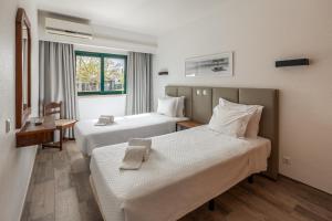 a hotel room with two beds and a window at Parque Monte Verde in Albufeira