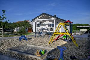 a playground with a swing set and a house at Holiday home Aprilis with pool, jacuzzi and sauna in Galovac