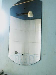a mirror in a bathroom with a white tiled wall at Vineyard Retreat Voi in Voi
