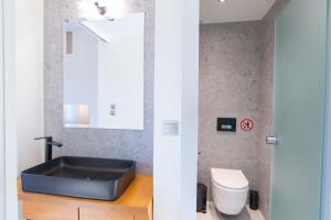 a bathroom with a black sink and a toilet at Olea Apartments Palioura Epanomi in Epanomi