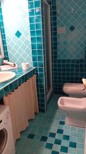 a blue tiled bathroom with a toilet and a sink at Rotondo Residence - Simar Vacanze in Porto Rotondo