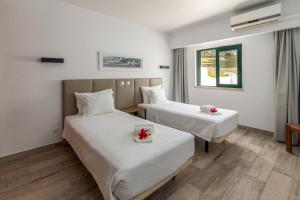 um quarto de hotel com duas camas com flores em Parque Monte Verde em Albufeira