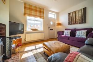 a living room with a purple couch and a tv at Langleys Cottage in Heacham