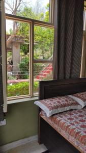 a bedroom with a window with a bed and a view at Blue Mountain Village Cottage in Nainital