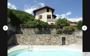 a house with a stone wall and a swimming pool at Casa Vista Lago in Sorico