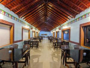 una sala da pranzo con tavoli, sedie e un grande soffitto di Desert King Resort a Dhordo