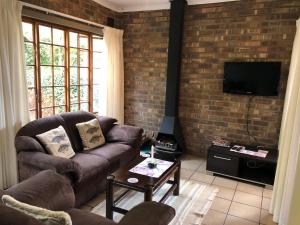 a living room with a couch and a brick wall at Cheerio Trout Fishing & Holiday Resort in Haenertsburg