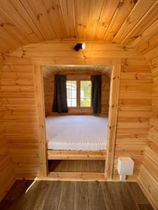 Bett in einem kleinen Zimmer in einer Holzhütte in der Unterkunft Naturcamping Lüneburger Heide - Chalets & Tiny Häuser in Soltau