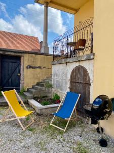 two lawn chairs and a grill in front of a house at Gîte de la maison jaune - Comblanchien in Comblanchien