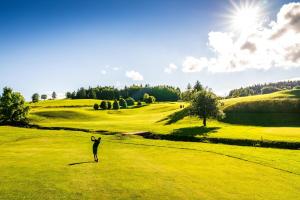 a woman standing on a green golf course at Le Chalain cosy proche centre ville in Les Rousses