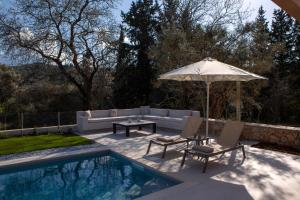 a patio with an umbrella and chairs and a pool at Luxury Villa Elpis in Lefkada