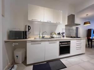 a kitchen with white cabinets and a sink and a microwave at Ebene Square apartment in Trianon