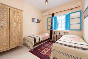 西迪布賽義德的住宿－Coup de cœur à Sidi Bou Said，一间卧室设有两张床、一个橱柜和一个窗口。