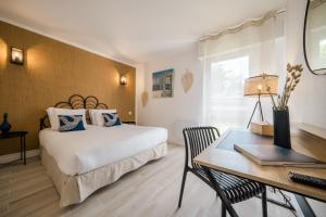a bedroom with a bed and a desk with a laptop at Hôtel de la Brière et Restaurant Les Krapados in Saint-Lyphard